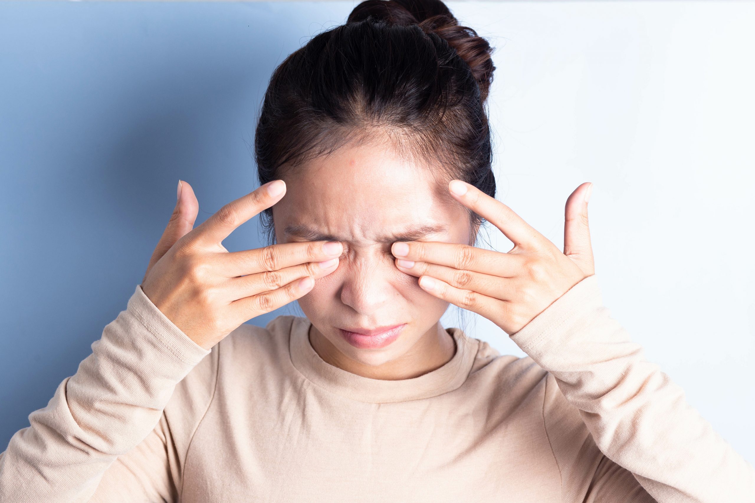 a young woman suffering from dry eye rubbing her eyes
